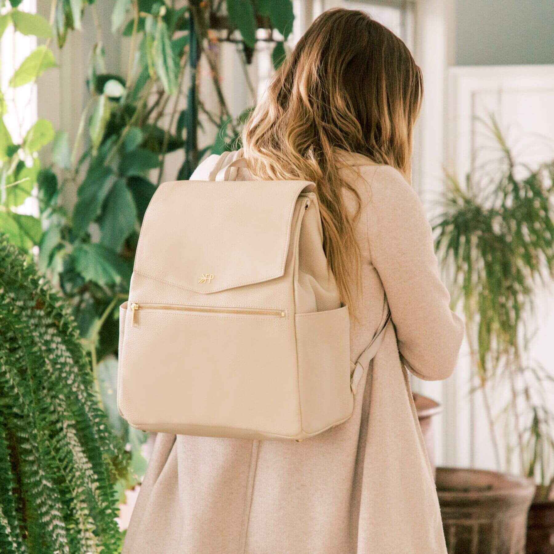 Woman wearing Freshly Picked Birch Classic Diaper Bag II in a plant-filled room