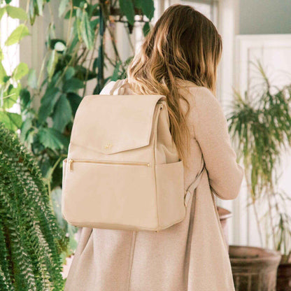 Woman wearing Freshly Picked Birch Classic Diaper Bag II in a plant-filled room