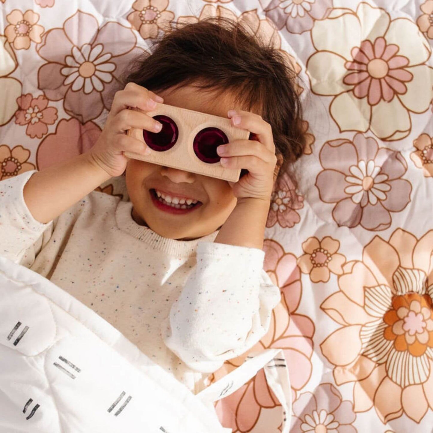 Kid holding a toy lying on Toki Kids Blooms Picnic Blanket