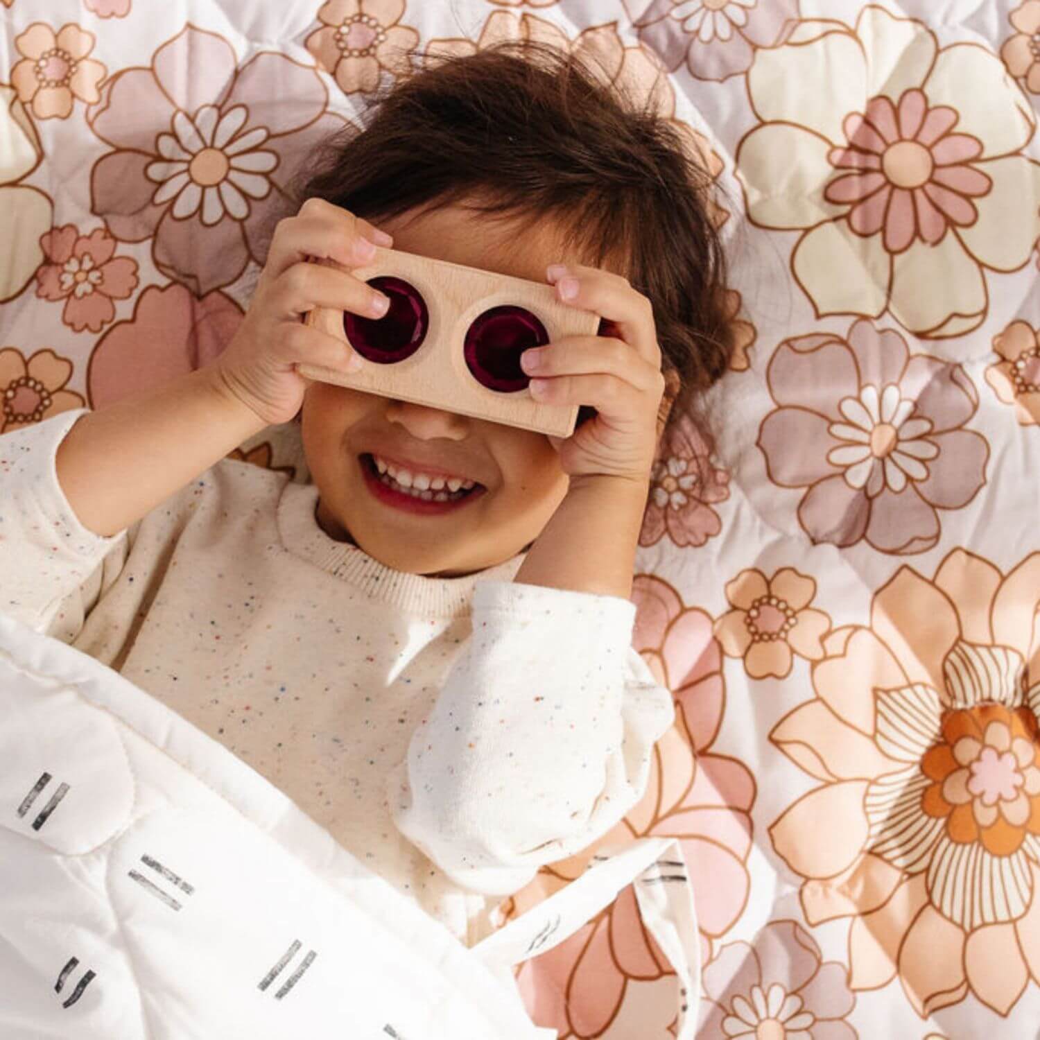 Kid holding a toy lying on Toki Kids Blooms Picnic Blanket