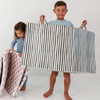 Two children holding a black and white striped mat against a white background