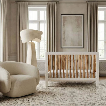 Modern nursery with a crib, armchair, and abstract art on the wall.