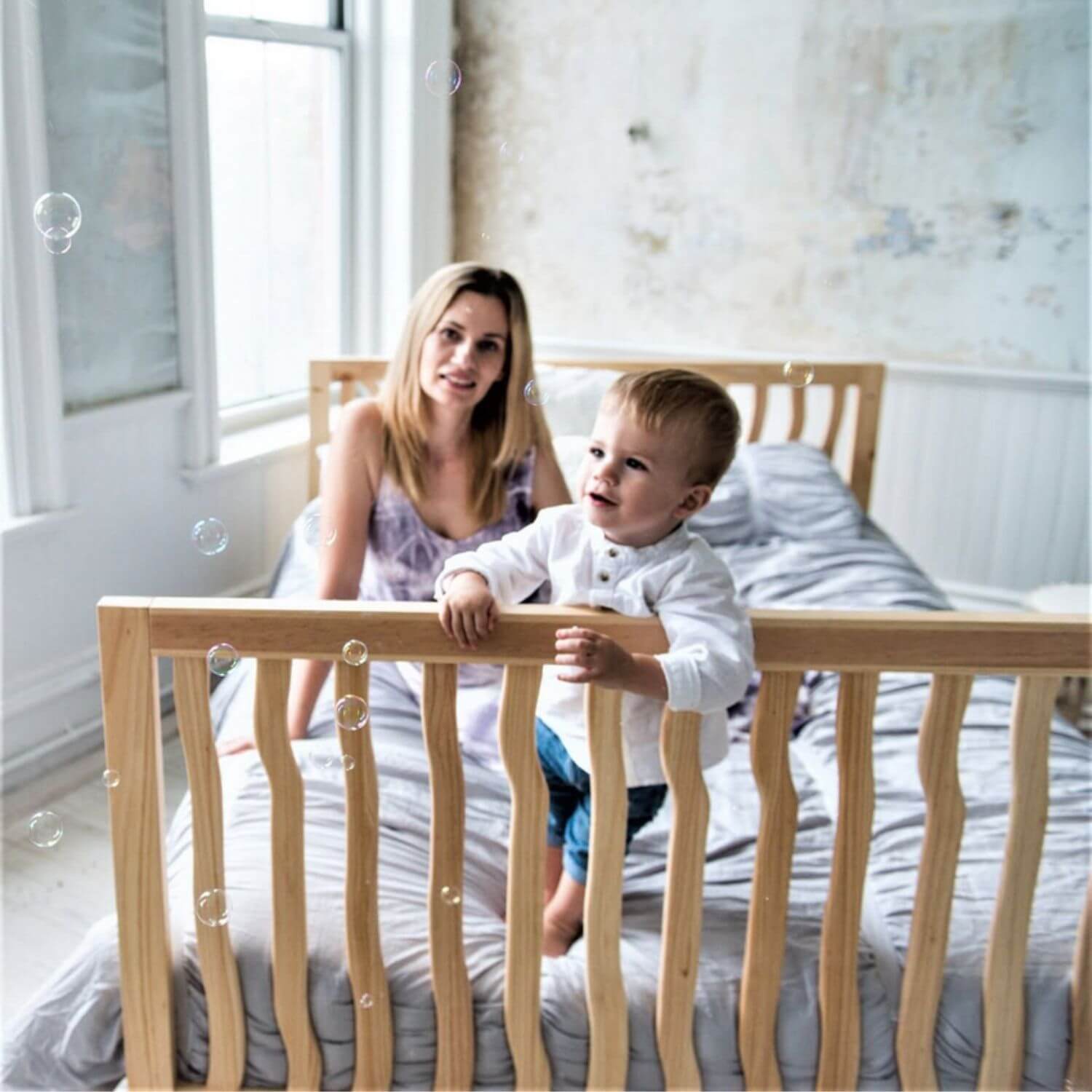 Woman and child on a bed with bubbles in a bright room
