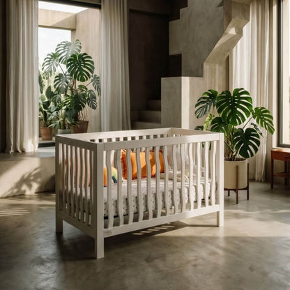 White crib in a modern room with plants and large windows