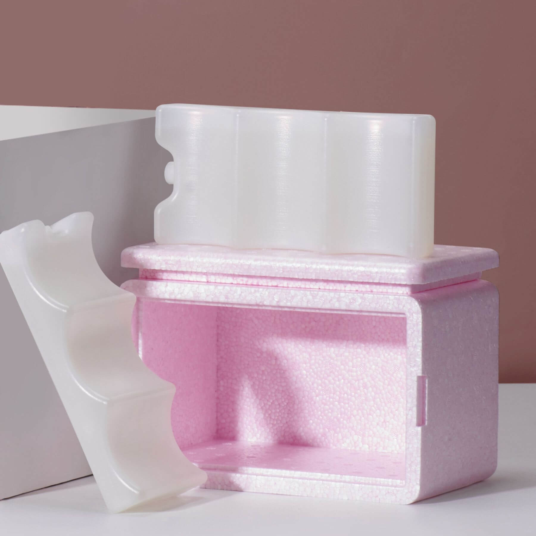 Pink and white foam packaging on a white surface with a pink background