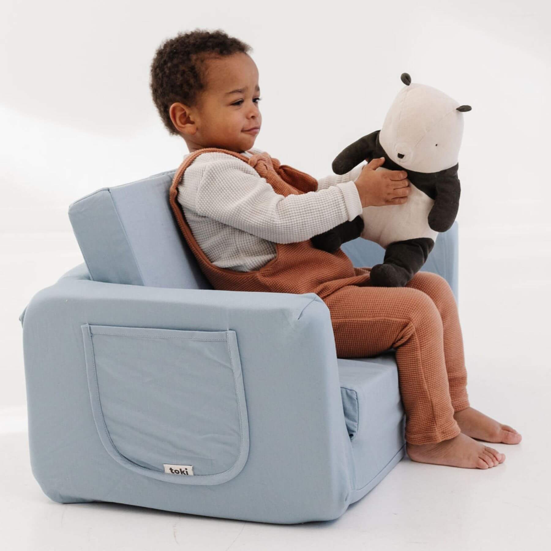 Child sitting on Toki Kids Breeze Play Couch holding a plush toy