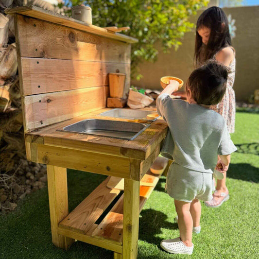 Children playing with Bunny Hopkins Mud Kitchen in a backyard.
