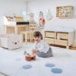 Child playing with a toy in a room with wooden furniture and toys.