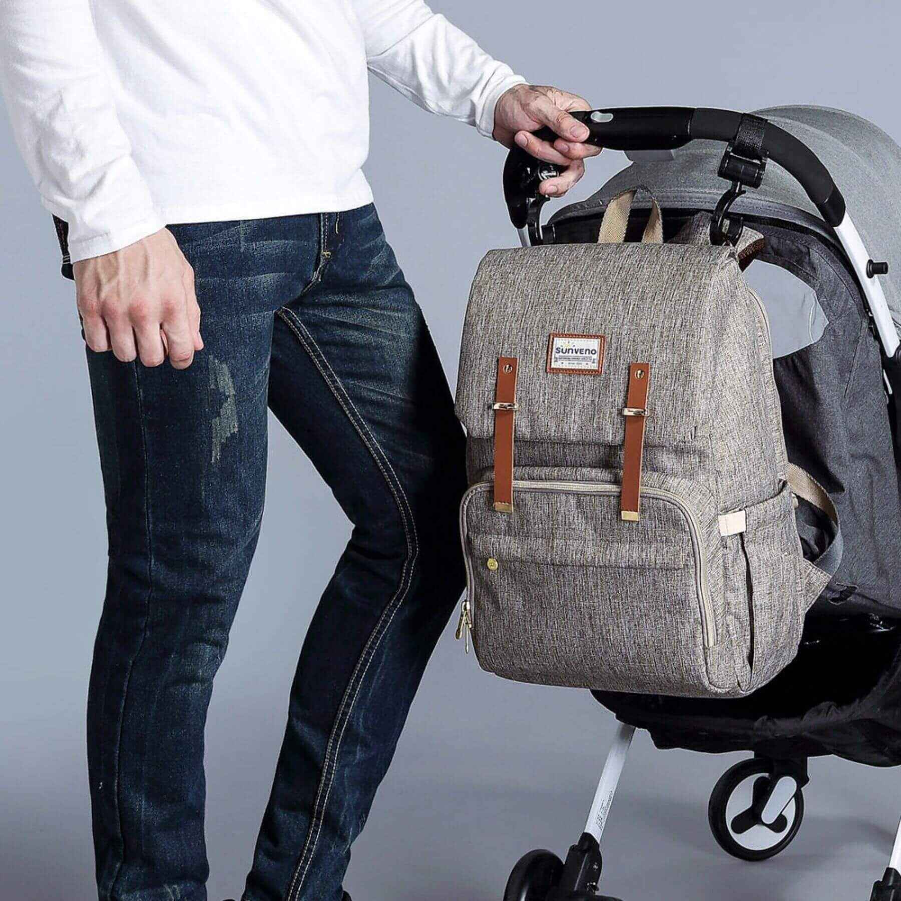 Man pushing a stroller with Sunveno Canvas Diaper Backpack - Brown