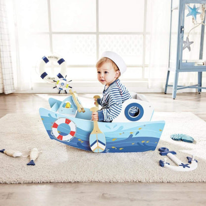 Child playing with Hape Captains Rocking Boat in a room with light wood flooring and white walls.