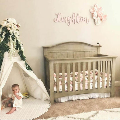 Baby crib with a child peeking out from a teepee in a nursery setting.