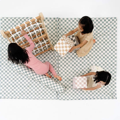 Three children playing on Toki Kids Checker Matcha Organic Cotton Mat with a wooden climbing toy.