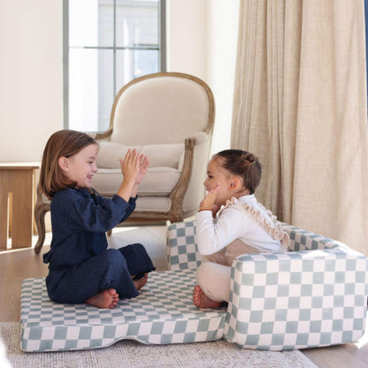 Two children playing on Toki Kids Checker Matcha Play Couch in a room with a chair and curtains.
