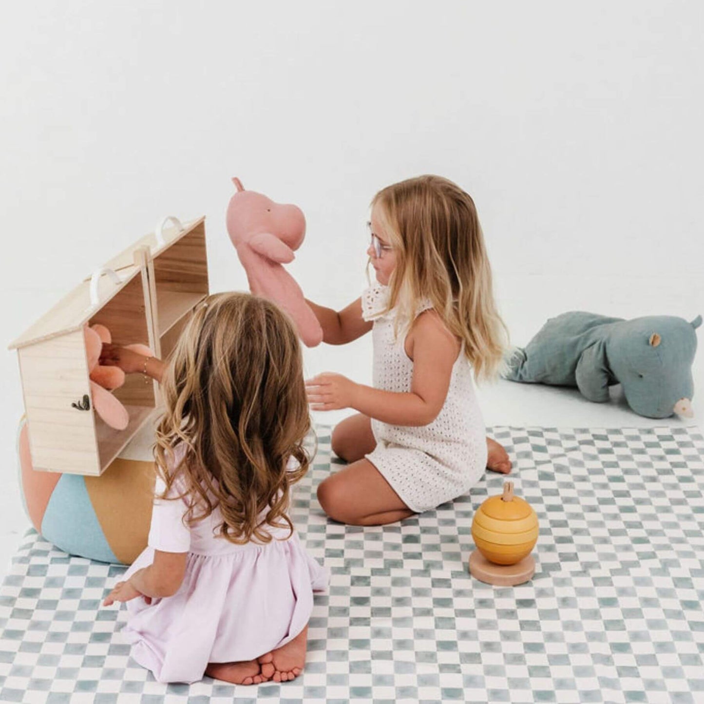 Two young children playing with toys on a checkered mat