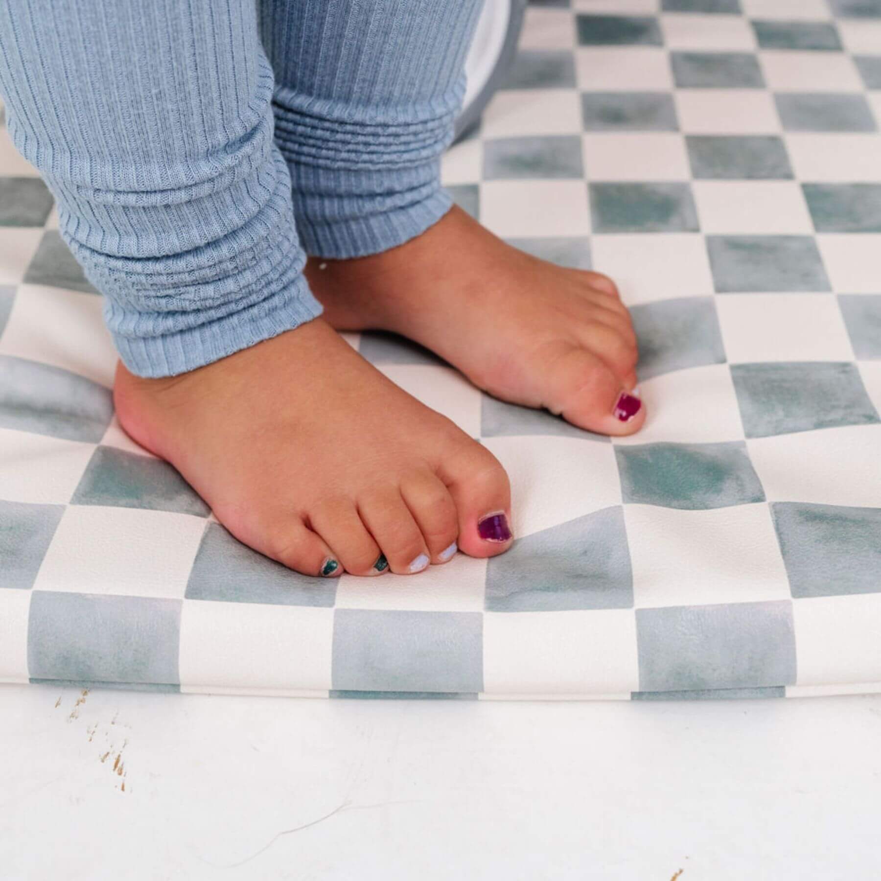 Child's feet with painted toenails on a checkered mat