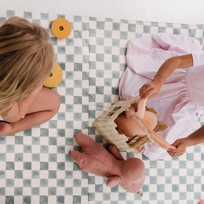 Two children playing with a baby doll on a checkered mat
