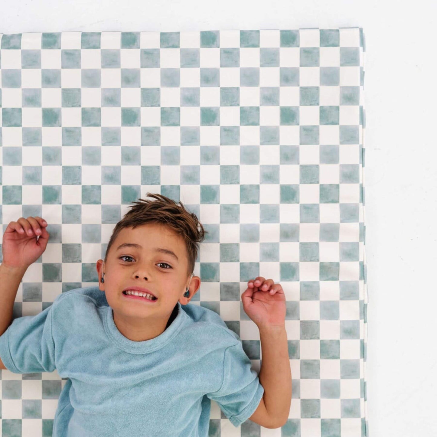 Child lying on a checkered mat with a blue and white pattern