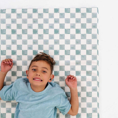 Child lying on a checkered mat with a blue and white pattern