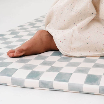 Baby foot on a checkered mat with a soft blanket