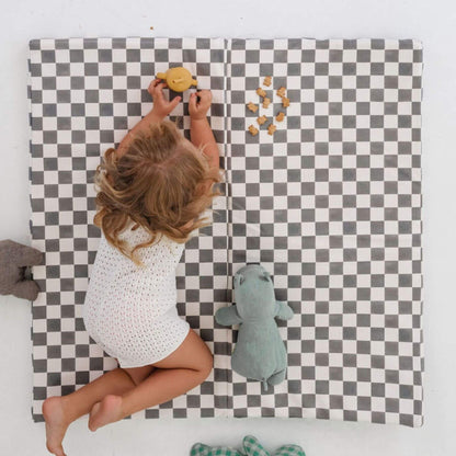 Child playing on a checkered mat with toys