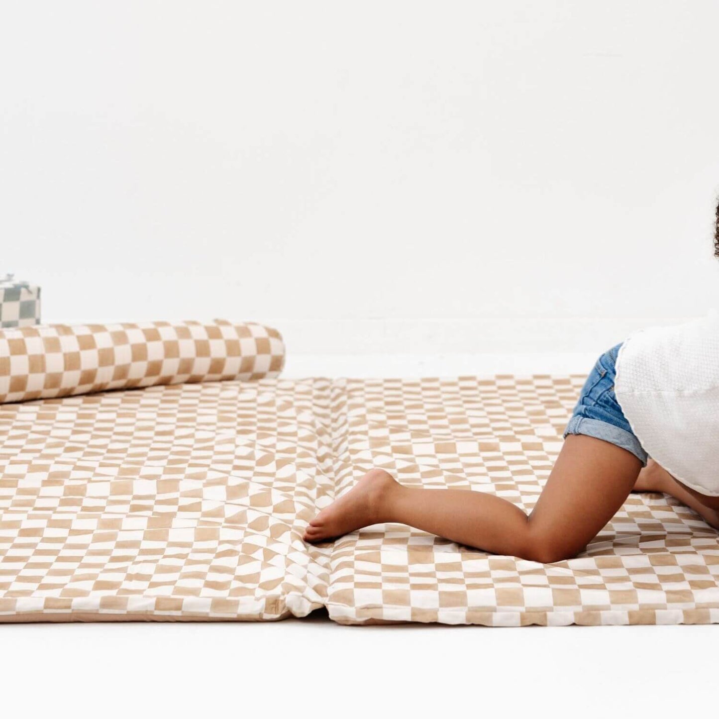 Person lying on Toki Kids Checker Toffee Organic Cotton Mat