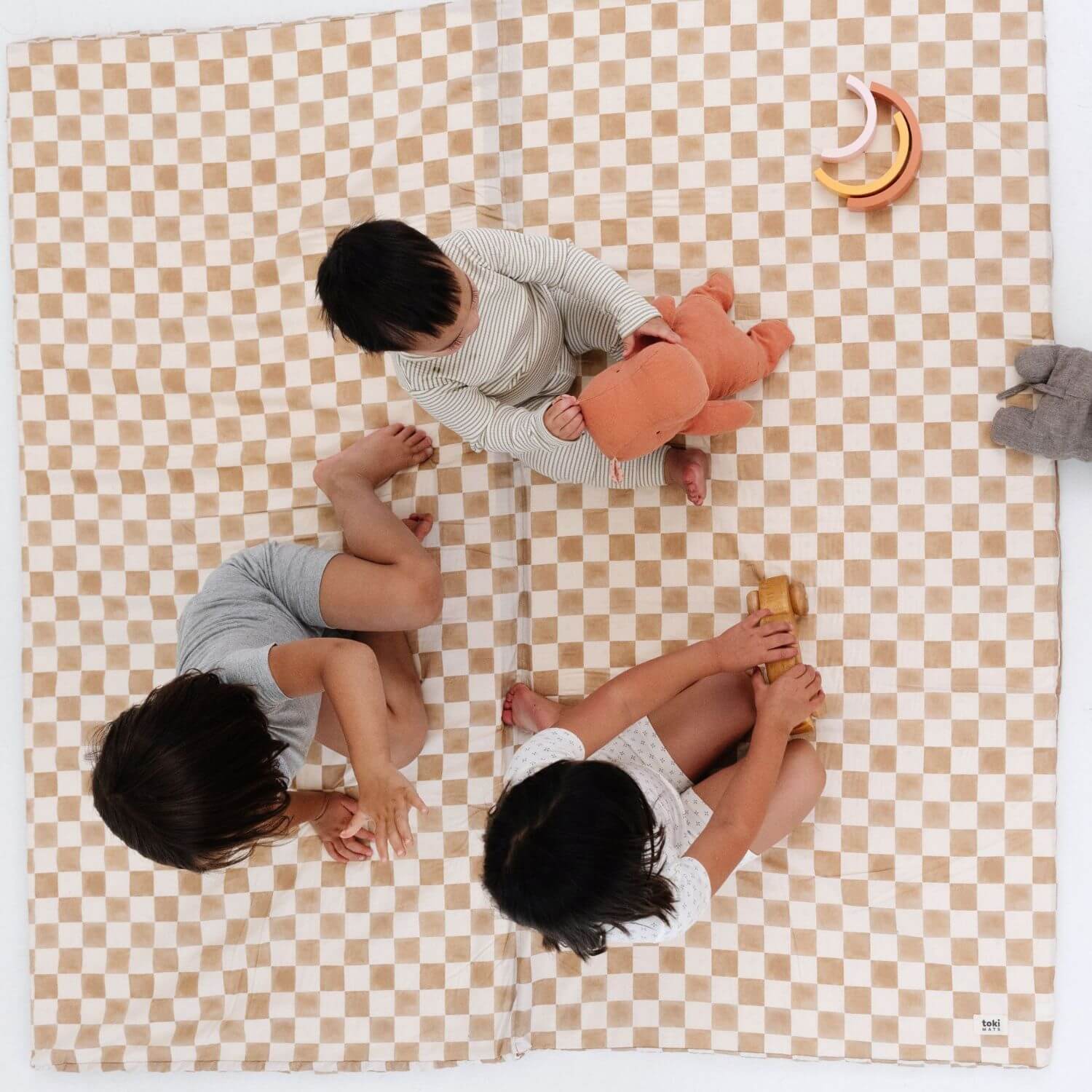 Three children playing on Toki Kids Checker Toffee Organic Cotton Mat