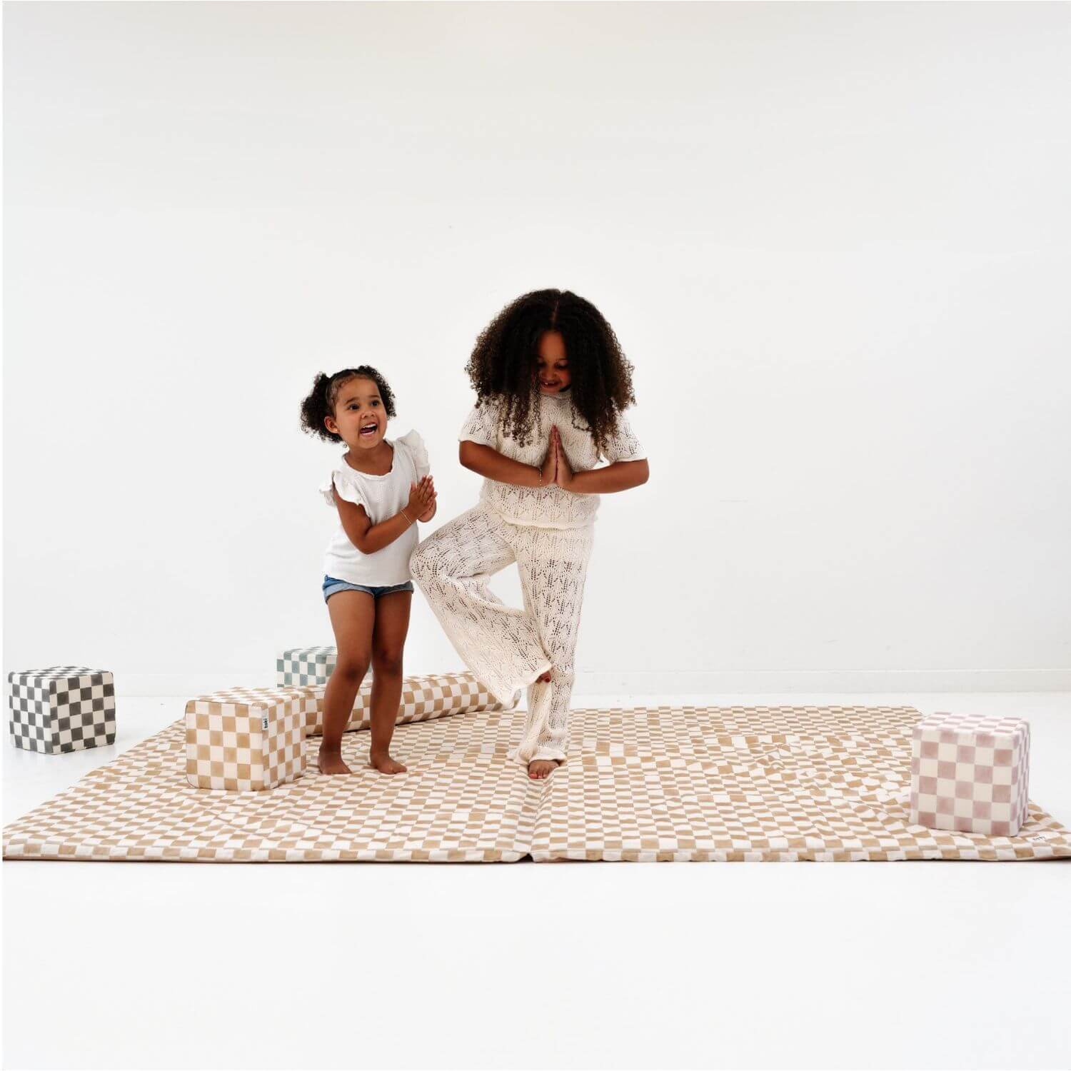 Two people practicing yoga on Toki Kids Checker Toffee Organic Cotton Mat