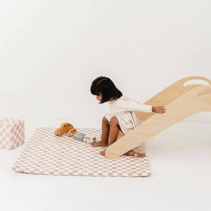 Child playing with a wooden slide and Toki Kids Checker Toffee Vegan Leather Mat on a white floor.