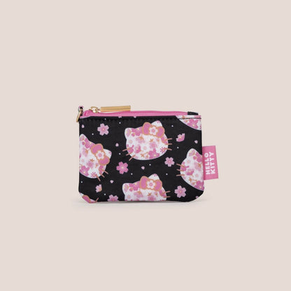 A small zippered pouch featuring a black background with a pink and white Hello Kitty floral pattern, shown on a solid light beige background.