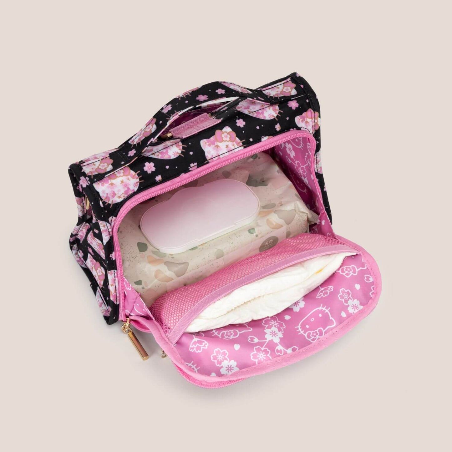 Hello Kitty® × JuJuBe Cherry Blossoms Bestie Small Messenger Handbag shown open, revealing a diaper holder inside with white tissue paper.