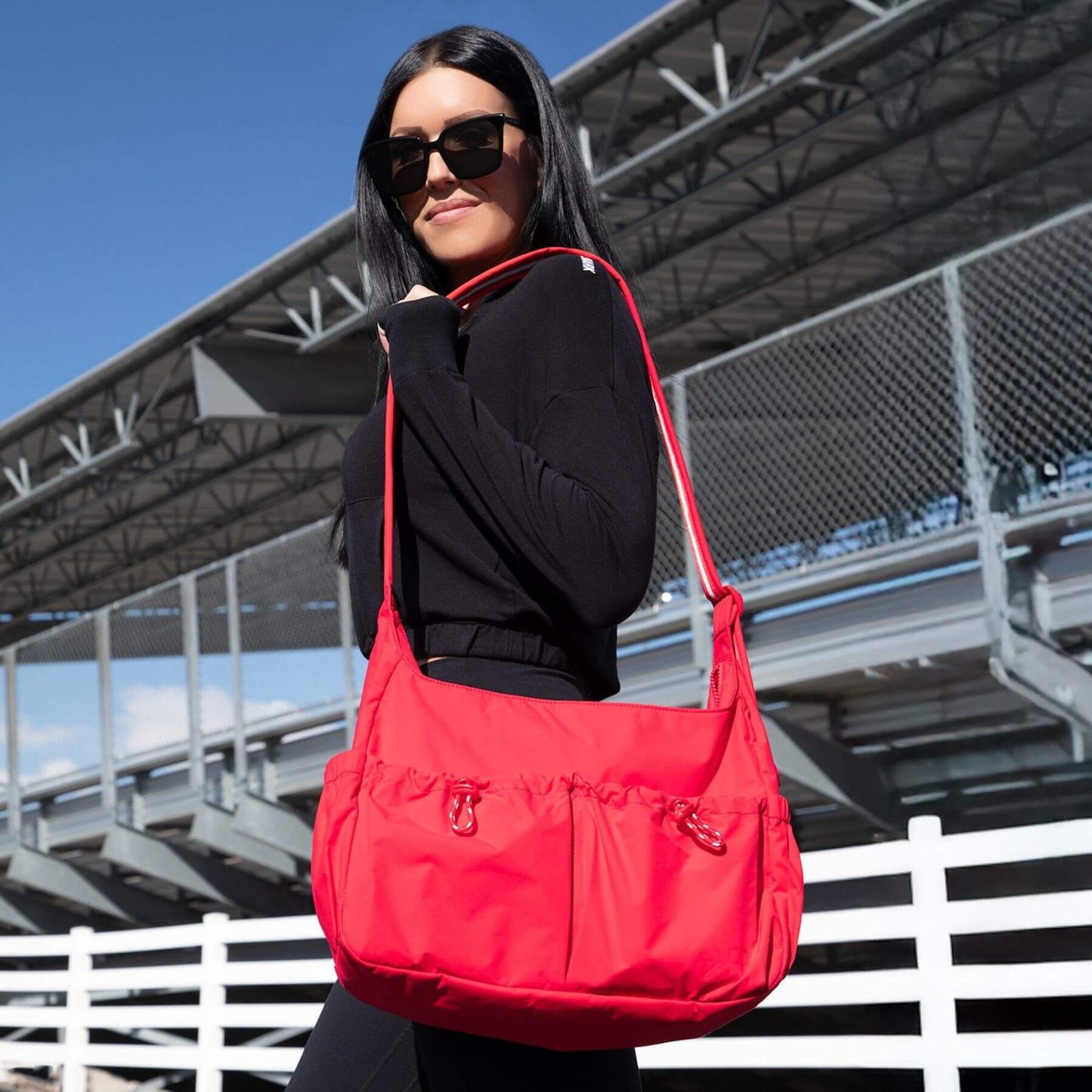 Woman carrying Cherry Motion Carryall Tote outdoors with a clear sky background
