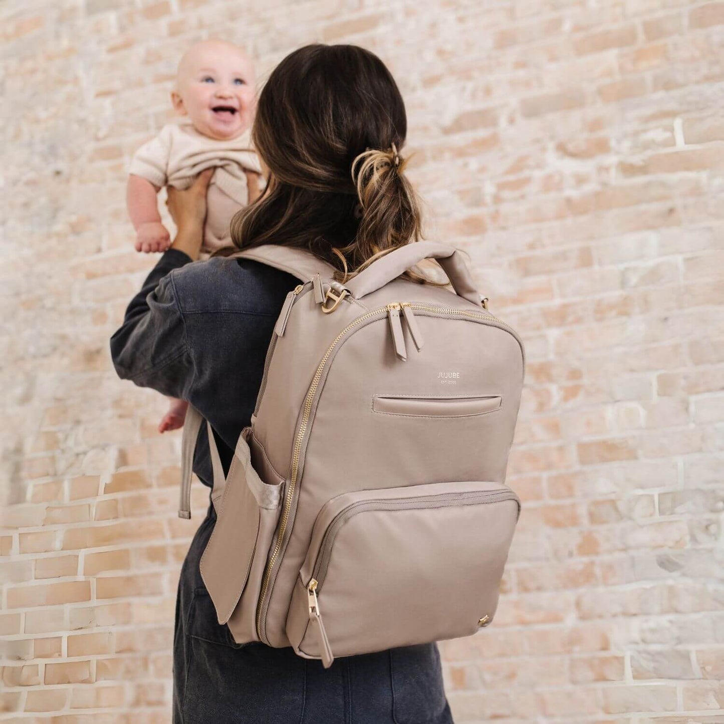 Woman Carrying JuJuBe Classic Diaper Backpack Taupe