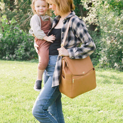 Woman holding a child and Butterscotch Classic Diaper Bag II in a park