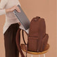 JuJuBe Classic Diaper Backpack Espresso on a stool with a person holding a laptop.