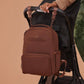 JuJuBe Classic Diaper Backpack Espresso attached to a stroller with a person holding it, on a beige background