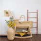 Plum+Sparrow Classic Rocking Moses Bassinet Stand with brake Natural, vase, and decorative items against a white wall.
