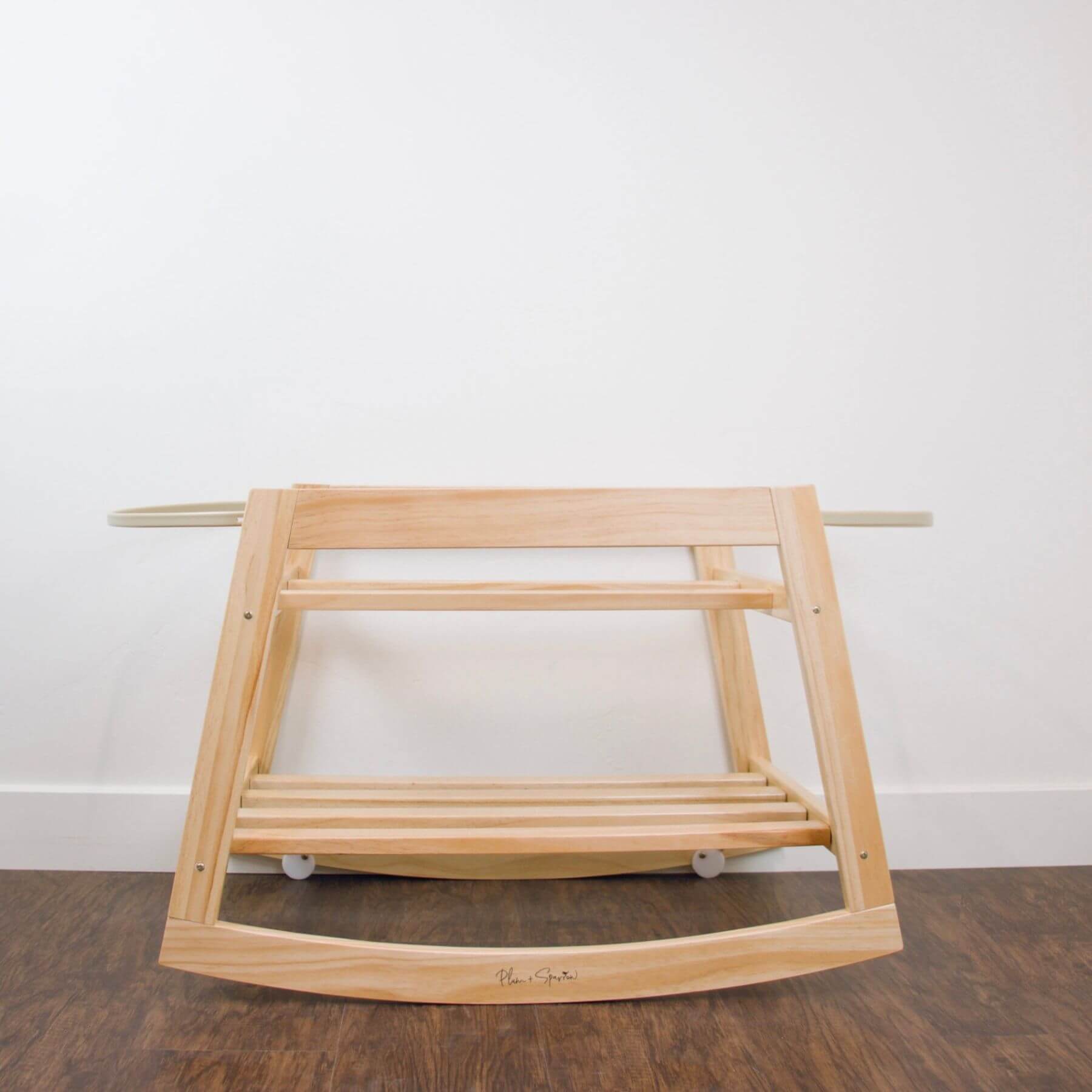 Plum+Sparrow Classic Rocking Moses Bassinet Stand with brake Natural on a wooden floor with a white wall background