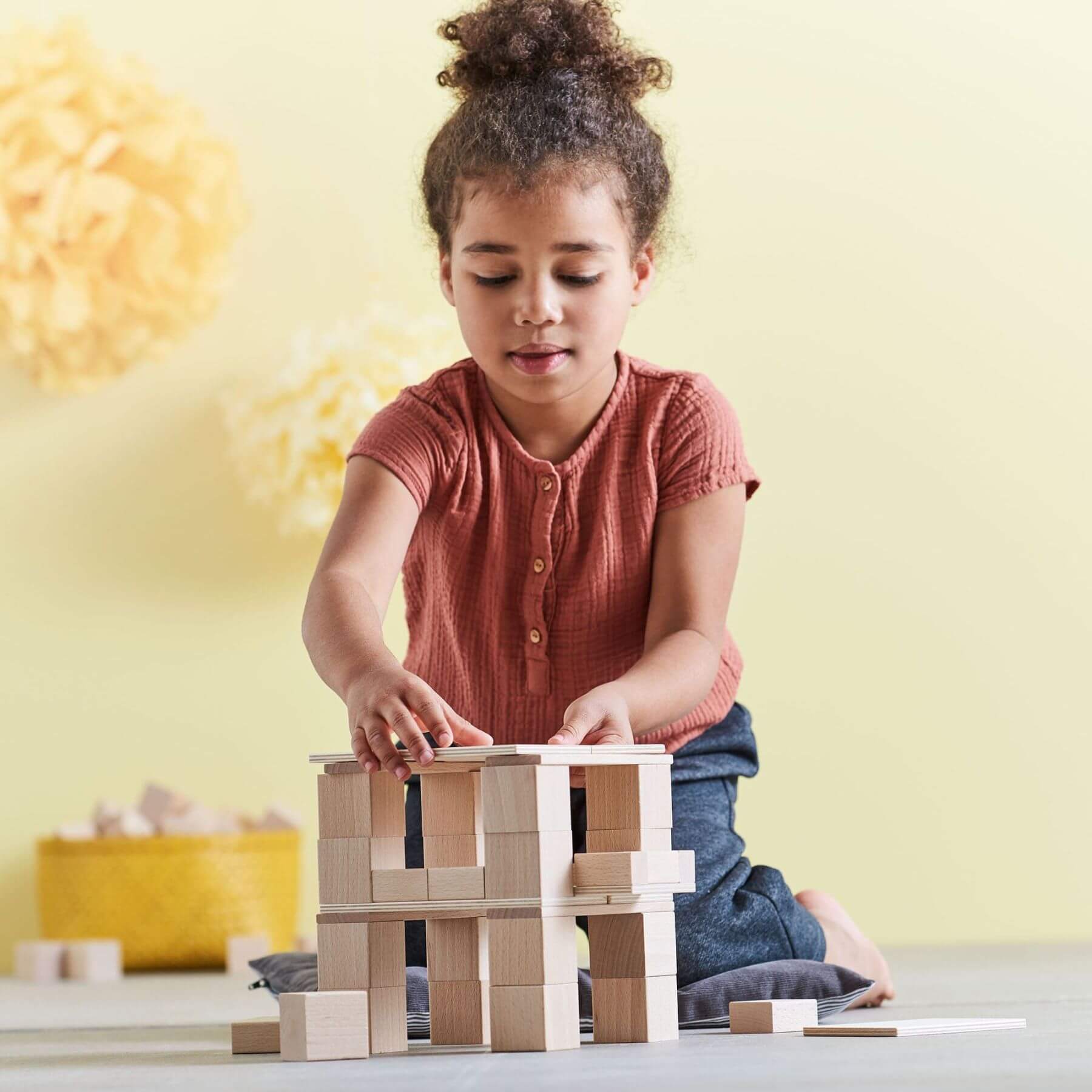 Child playing with HABA USA Clever Up! Building Block System 3.0 on a light-colored surface with a yellow wall in the background