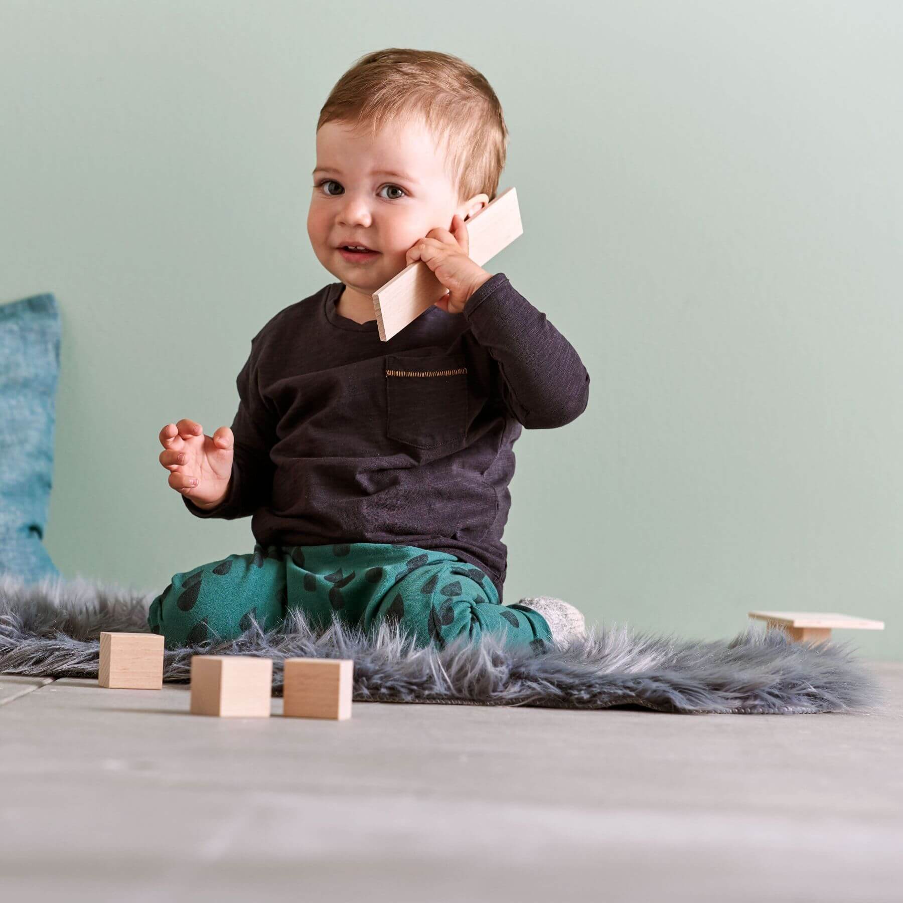 Child playing with wooden blocks on a light-colored surface.