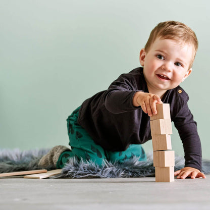 Child playing with wooden blocks on a light surface with a neutral background