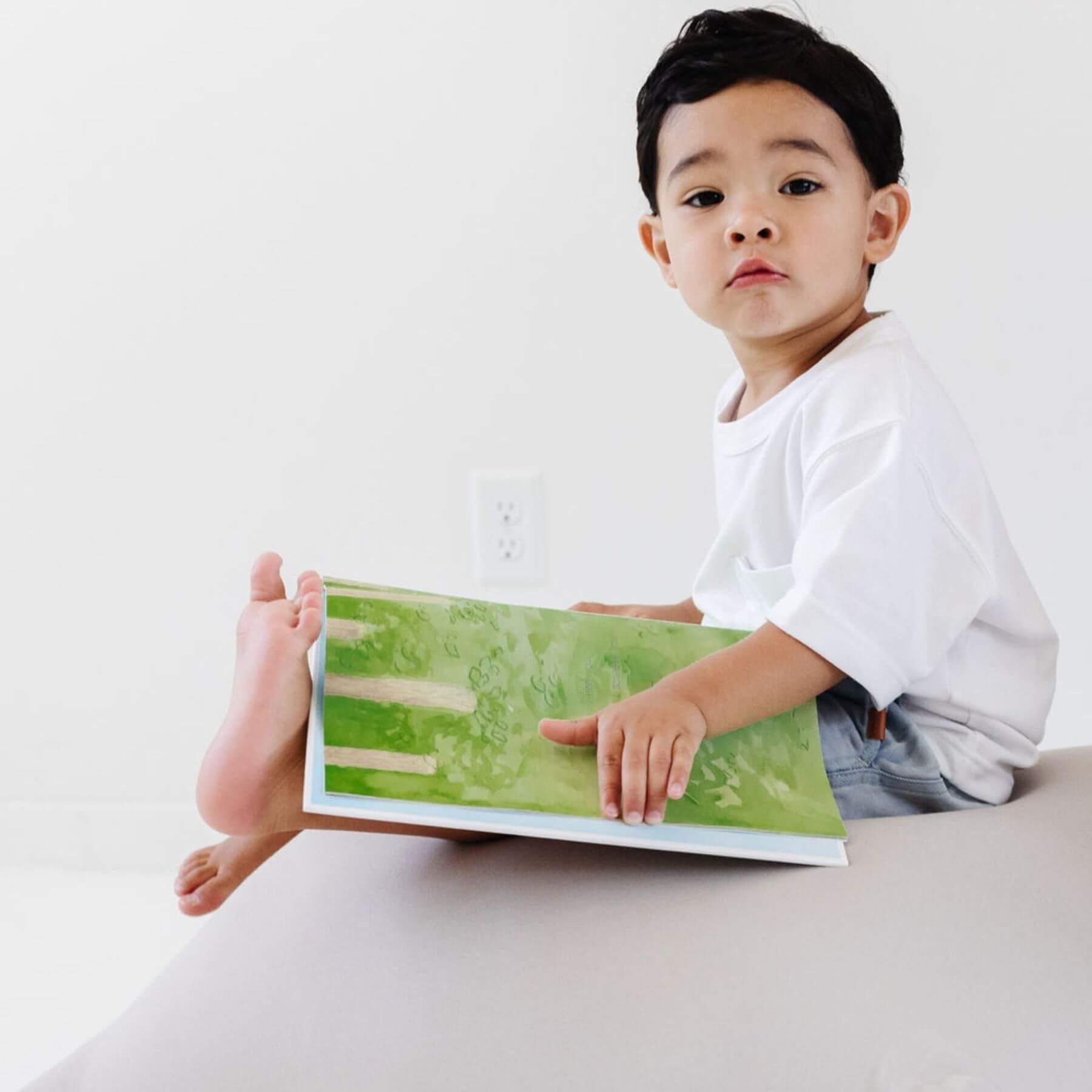 Child holding a book sitting on Toki Kids Cloud Bean Bag