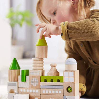Child playing with HABA USA Coburg 28 Piece Wooden Building Blocks in a blurred indoor setting