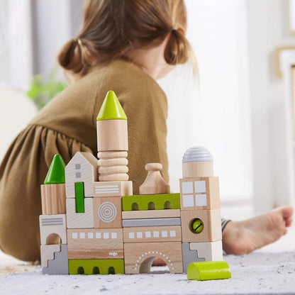 Child playing with HABA USA Coburg 28 Piece Wooden Building Blocks on a light surface.