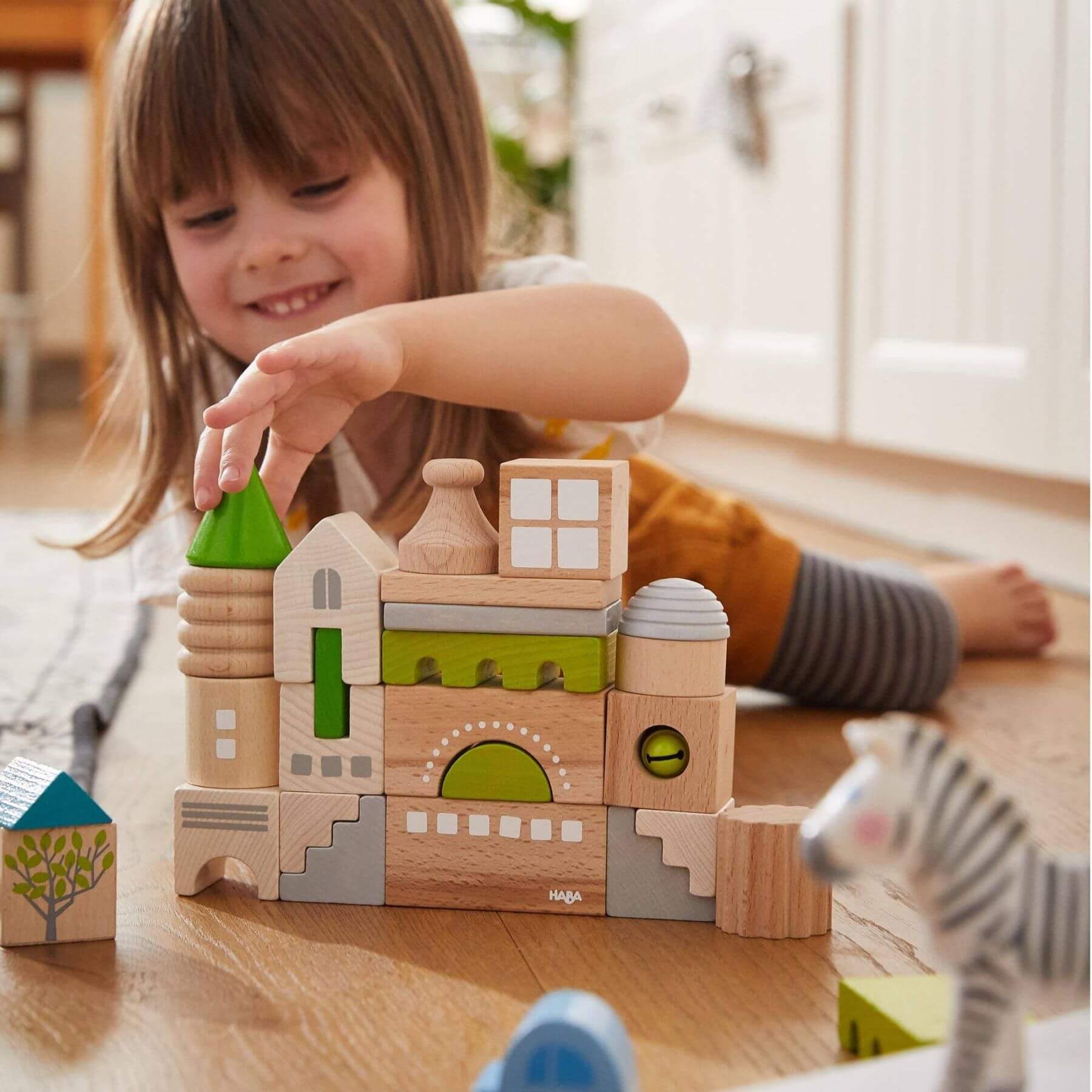 Child playing with HABA USA Coburg 28 Piece Wooden Building Blocks on a wooden floor
