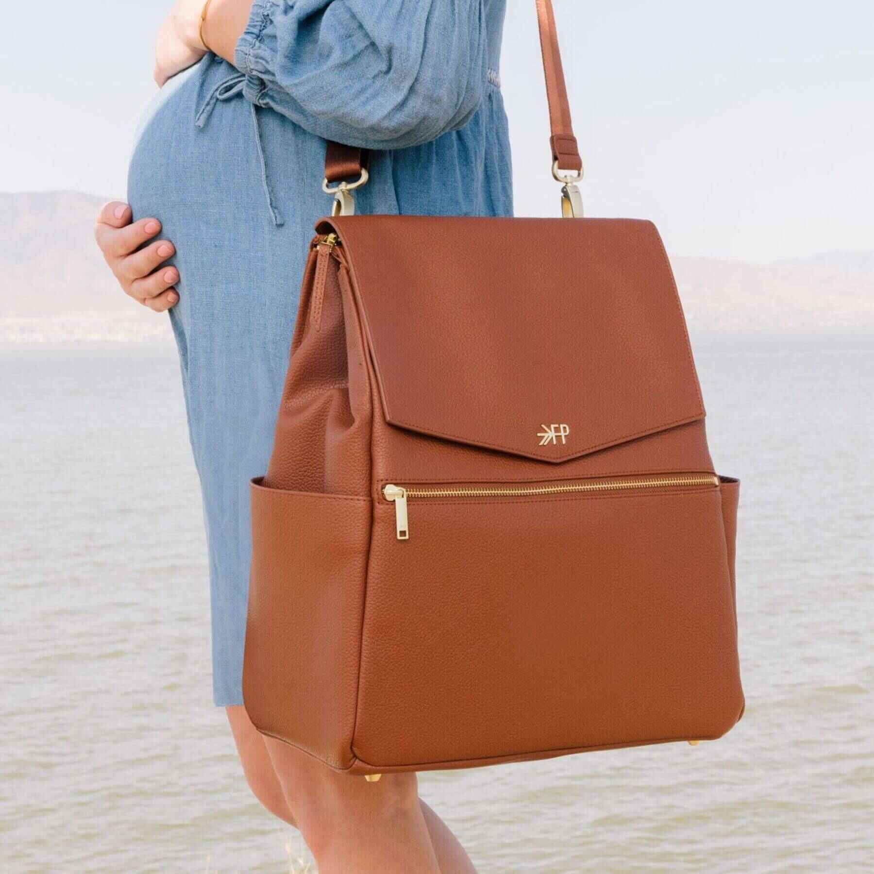 Cognac Classic Diaper Bag II held by a person wearing a blue dress.