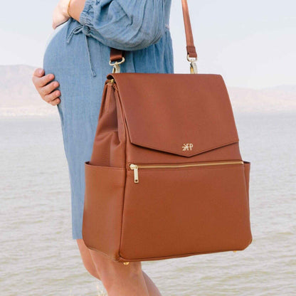 Cognac Classic Diaper Bag II held by a person wearing a blue dress.