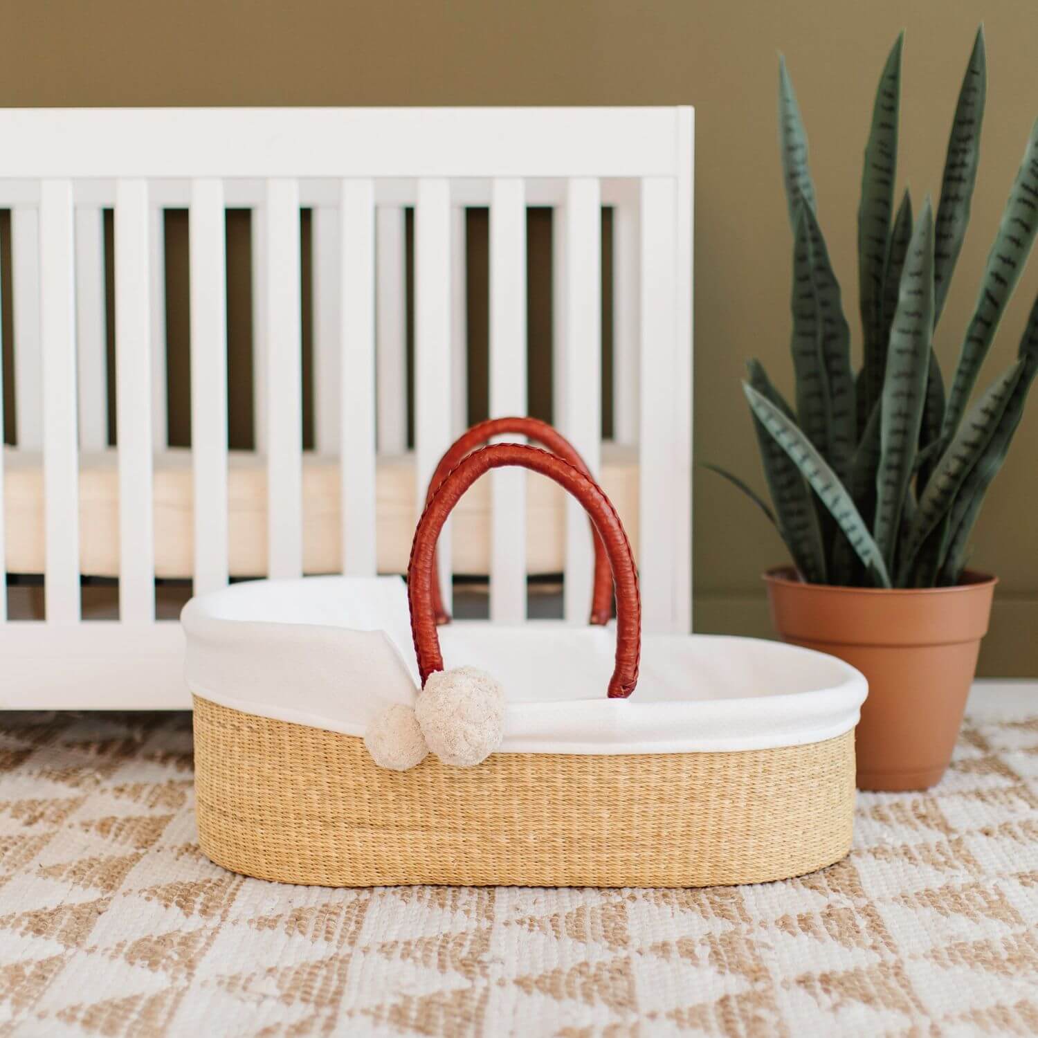 Plum+Sparrow Cognac Handle Moses Basket in front of crib