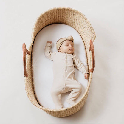 Baby sleeping in Plum+Sparrow Cognac Handle Moses Basket