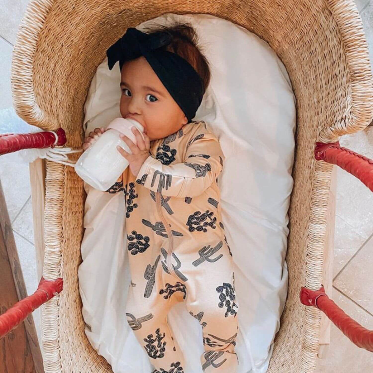 Baby lying in Plum+Sparrow Cognac Handle Moses Basket