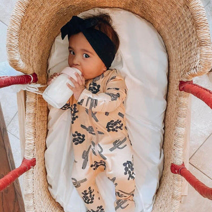 Baby lying in Plum+Sparrow Cognac Handle Moses Basket